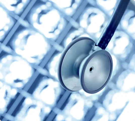 Close-up of a stethoscope with medical diagnostic scans in the background.